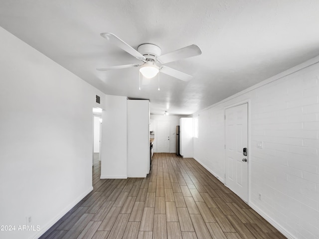 unfurnished room featuring ceiling fan, wood-type flooring, a textured ceiling, and brick wall