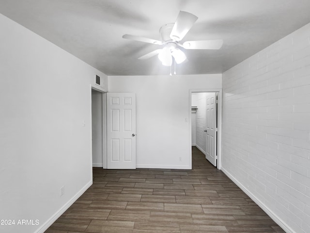 unfurnished bedroom featuring brick wall, dark hardwood / wood-style floors, a closet, and ceiling fan