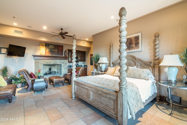 bedroom with ceiling fan and a stone fireplace