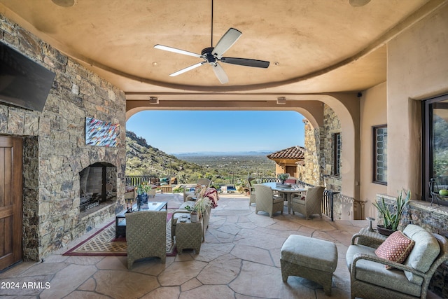 view of patio / terrace with ceiling fan, a mountain view, and an outdoor stone fireplace