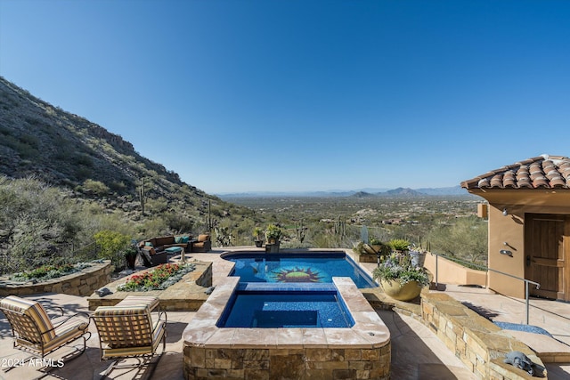 view of pool with a patio, an in ground hot tub, and a mountain view