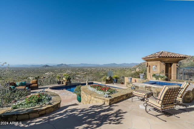 view of patio with a pool with hot tub and a mountain view