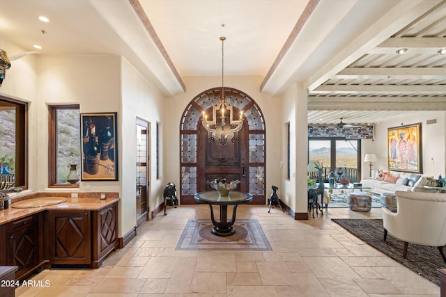 foyer entrance featuring beamed ceiling and a notable chandelier