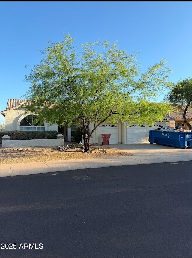 12955 E Sahuaro Dr, Scottsdale, AZ 85259 - view of property hidden behind natural elements featuring an attached garage, concrete driveway, and stucco siding