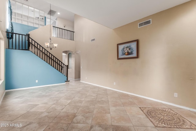 unfurnished living room featuring a high ceiling, a chandelier, and light tile patterned flooring