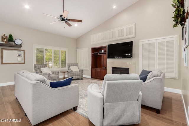 living room featuring ceiling fan, high vaulted ceiling, light wood-type flooring, and a fireplace