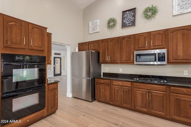 kitchen with a high ceiling, dark stone countertops, and black appliances