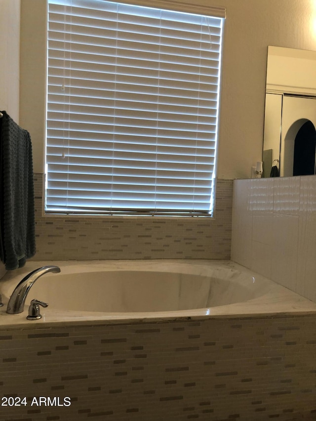 bathroom featuring a healthy amount of sunlight and tiled tub