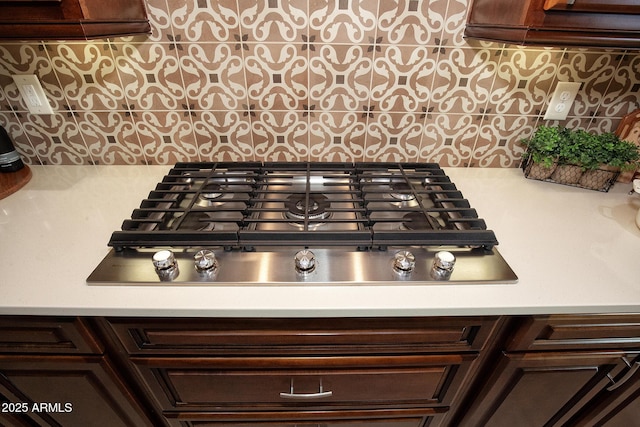 room details with dark brown cabinets, stainless steel gas cooktop, and backsplash