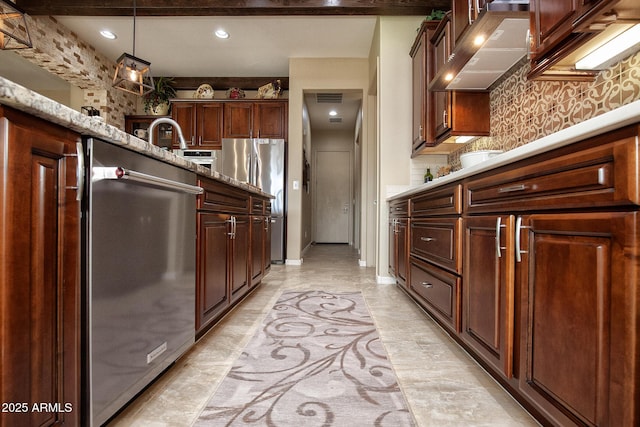 kitchen featuring stainless steel refrigerator, hanging light fixtures, light stone counters, extractor fan, and decorative backsplash