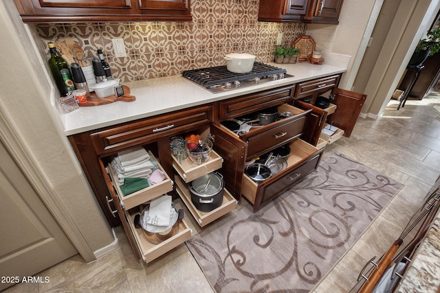 details with stainless steel gas stovetop and decorative backsplash