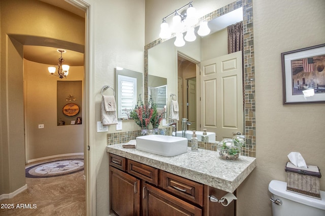 bathroom with vanity, a notable chandelier, decorative backsplash, and toilet