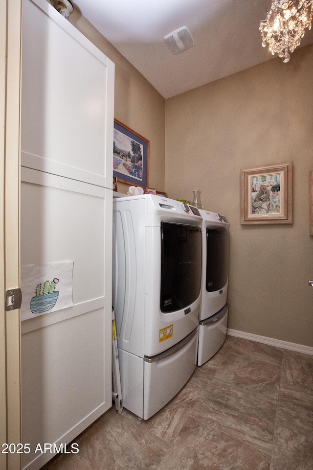 washroom featuring cabinets, a notable chandelier, and washing machine and clothes dryer