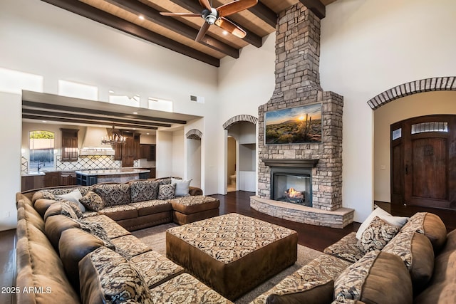 living room with sink, ceiling fan, hardwood / wood-style floors, a fireplace, and beamed ceiling