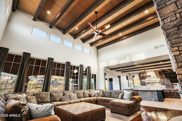 living room with beamed ceiling, a high ceiling, light hardwood / wood-style floors, a healthy amount of sunlight, and wooden ceiling