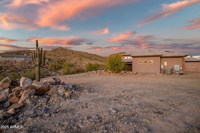 yard at dusk with a mountain view and central AC unit