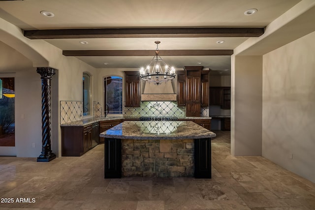 kitchen featuring a kitchen island, tasteful backsplash, dark stone countertops, hanging light fixtures, and dark brown cabinetry