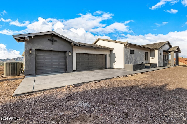 view of front of property featuring a garage, central air condition unit, and a mountain view