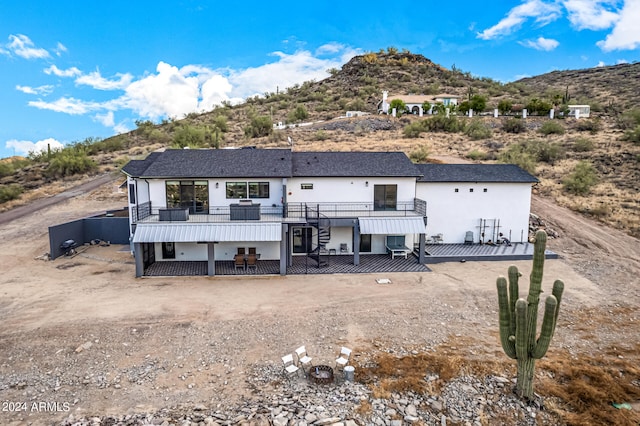 rear view of property with a balcony and a deck with mountain view