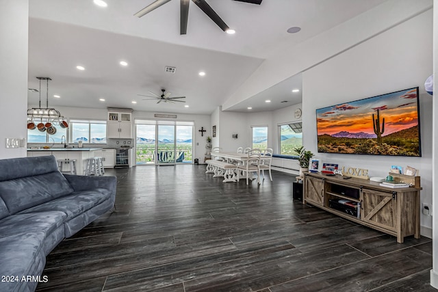 living room featuring vaulted ceiling, dark hardwood / wood-style floors, ceiling fan, and plenty of natural light