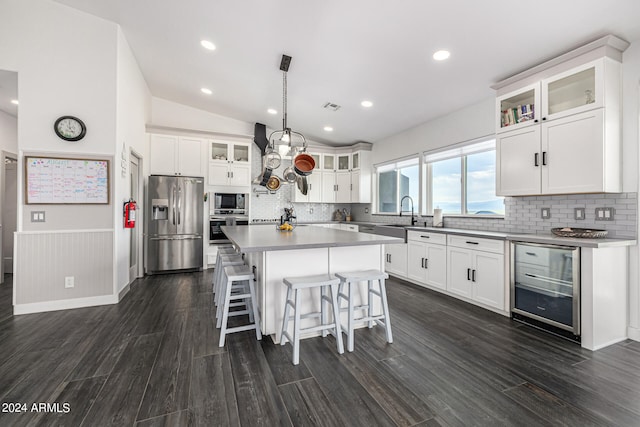 kitchen featuring wine cooler, a center island, hanging light fixtures, appliances with stainless steel finishes, and dark hardwood / wood-style flooring