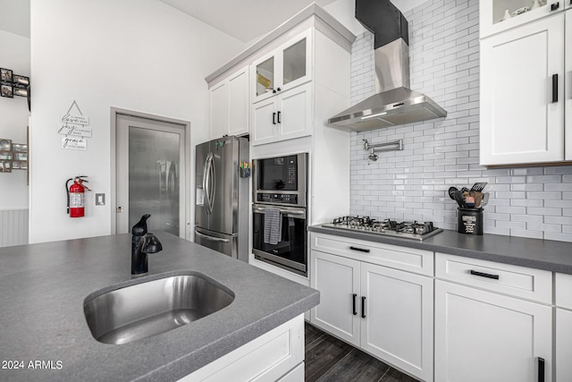 kitchen with white cabinets, appliances with stainless steel finishes, wall chimney range hood, and sink