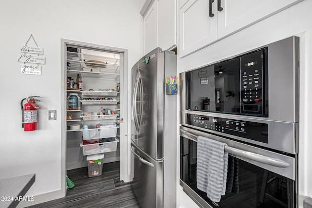 kitchen with appliances with stainless steel finishes, dark hardwood / wood-style flooring, and white cabinetry