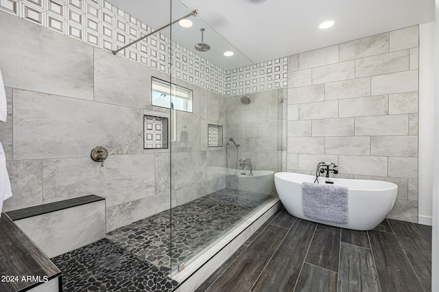 bathroom featuring plus walk in shower and tile walls