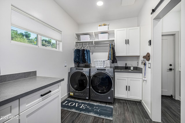 clothes washing area featuring sink, dark wood-type flooring, cabinets, separate washer and dryer, and a barn door