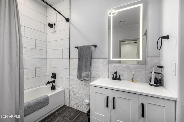 bathroom with shower / bath combo with shower curtain, tile walls, hardwood / wood-style flooring, and vanity