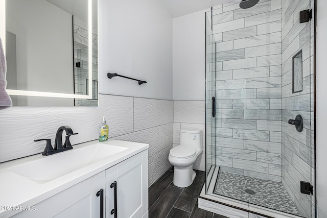 bathroom featuring vanity, a shower with shower door, hardwood / wood-style flooring, tile walls, and toilet