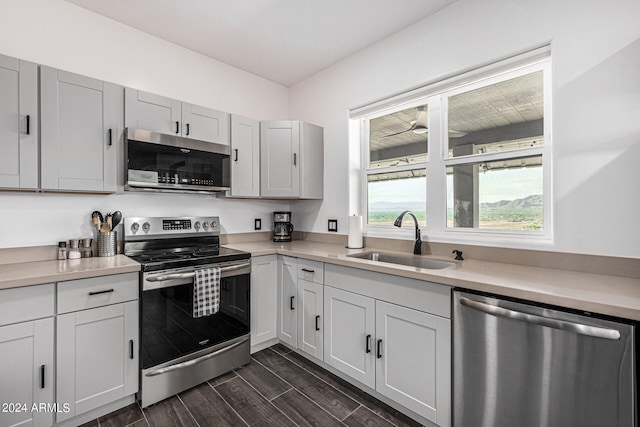 kitchen with stainless steel appliances, white cabinetry, sink, and dark hardwood / wood-style flooring