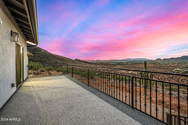 patio terrace at dusk featuring a balcony and a mountain view