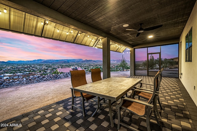 patio terrace at dusk featuring a mountain view and ceiling fan