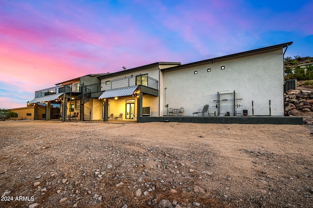 back house at dusk with a wooden deck and a patio area