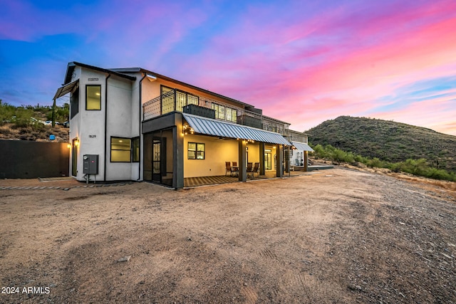 back house at dusk with a balcony and a mountain view