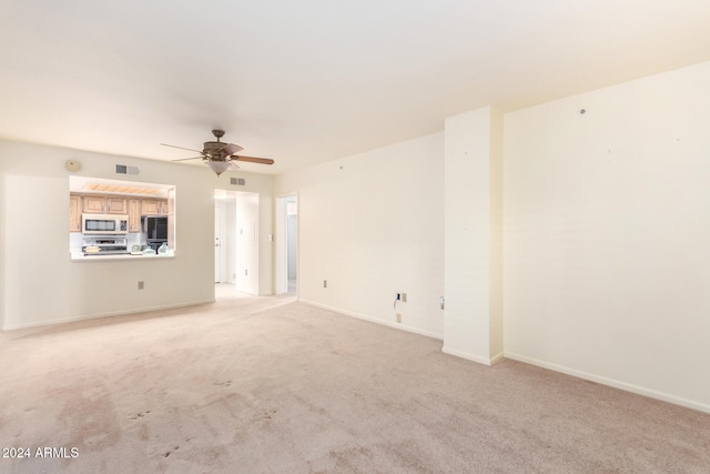 unfurnished living room with light colored carpet and ceiling fan