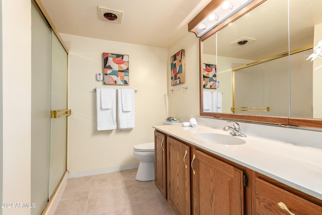 bathroom with tile patterned flooring, vanity, a shower with shower door, and toilet