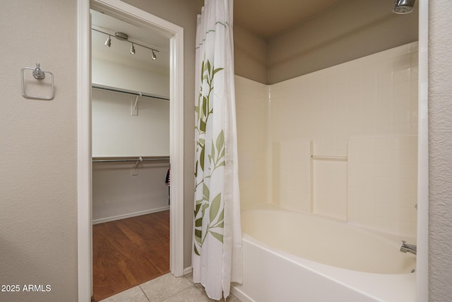 full bath featuring a walk in closet, tile patterned floors, and shower / tub combo