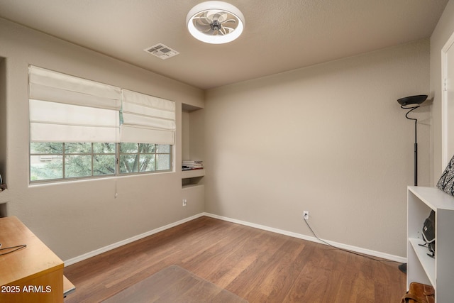 interior space featuring visible vents, baseboards, and wood finished floors