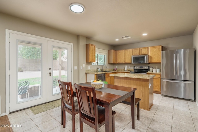 kitchen featuring visible vents, a sink, french doors, appliances with stainless steel finishes, and a center island