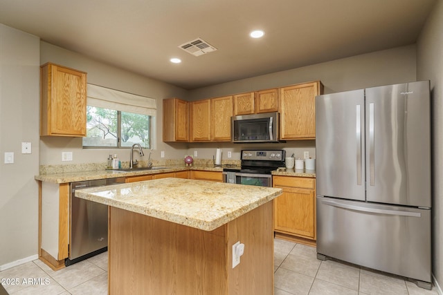 kitchen featuring visible vents, a kitchen island, light tile patterned floors, stainless steel appliances, and a sink