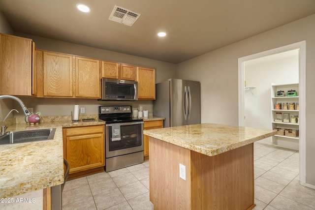 kitchen featuring visible vents, a center island, light tile patterned floors, stainless steel appliances, and a sink