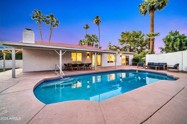 pool at dusk with an outdoor hangout area and a patio