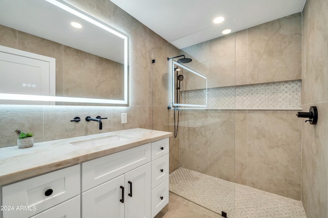 bathroom featuring vanity, tiled shower, and tile walls