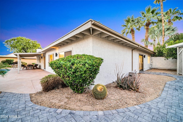 property exterior at dusk featuring a patio