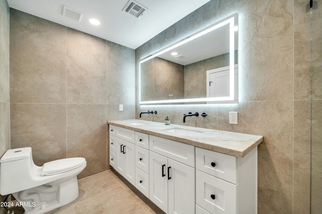 bathroom with tile patterned floors, vanity, toilet, and tile walls