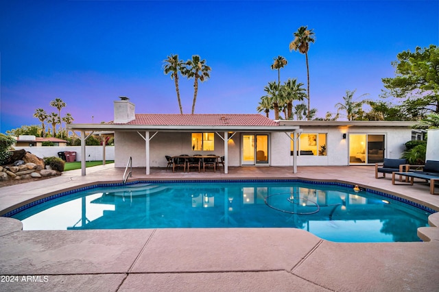 pool at dusk with a patio area