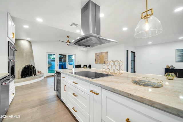 kitchen featuring island exhaust hood, black electric stovetop, light stone counters, decorative light fixtures, and white cabinets