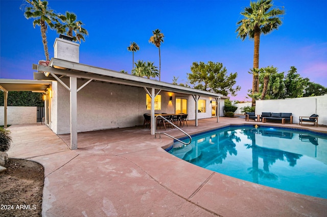 pool at dusk with an outdoor living space and a patio area